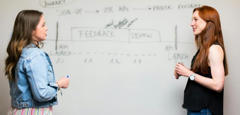 photo of women talking beside whiteboard